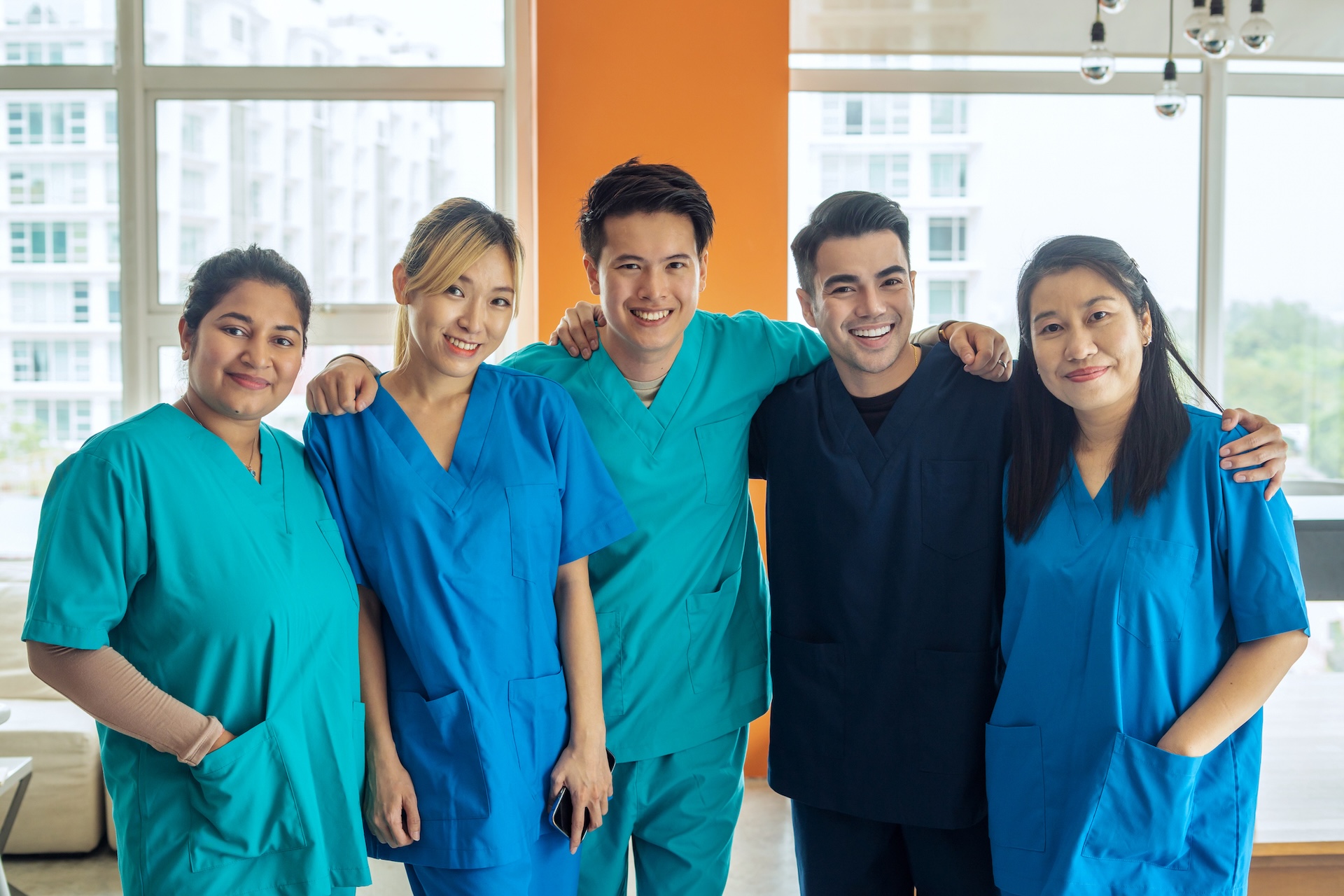 Five diverse nursing students in medical scrubs.