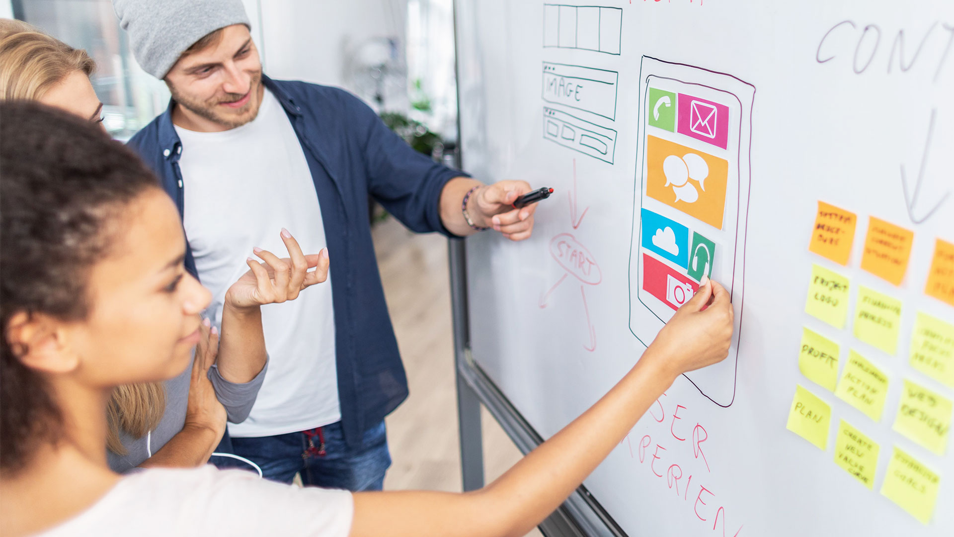 A group of students learn and discuss about wireframes on a whiteboard.