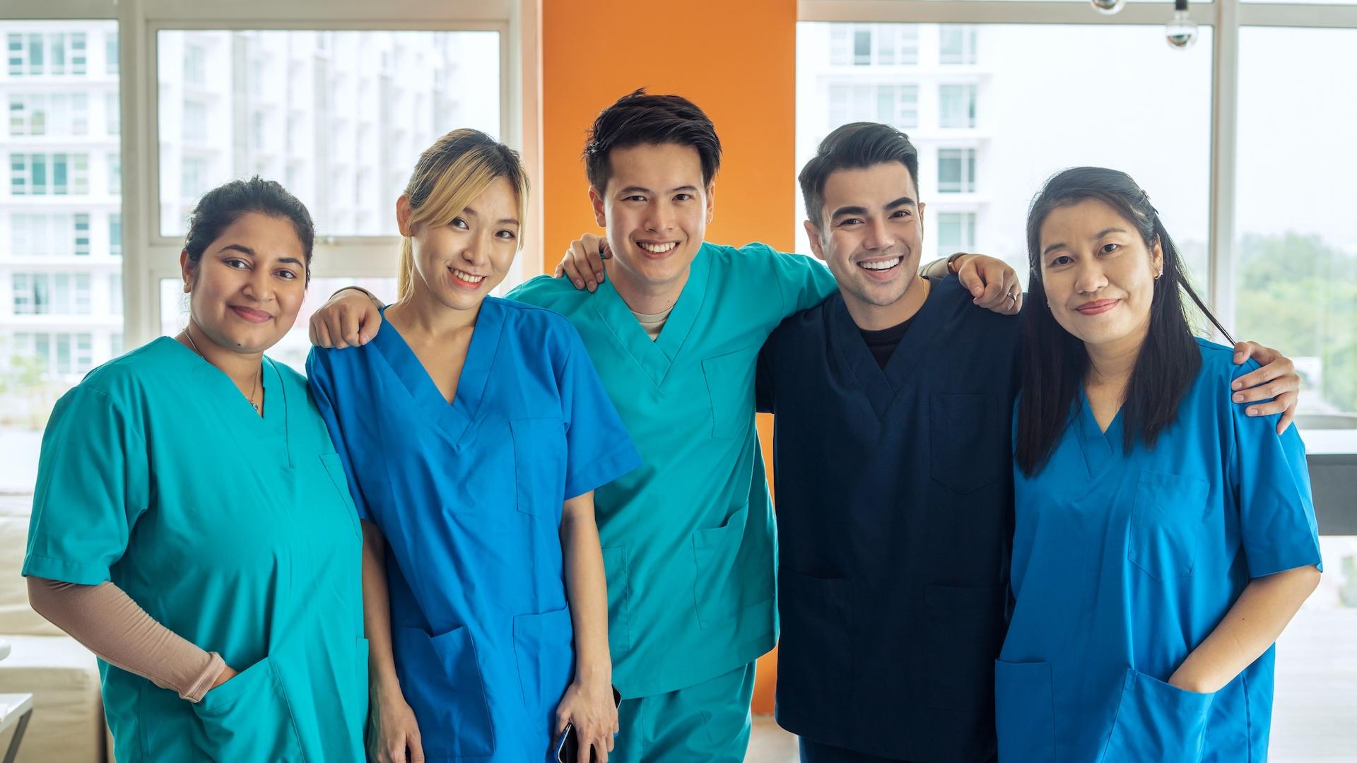 Five diverse nursing students in medical scrubs.
