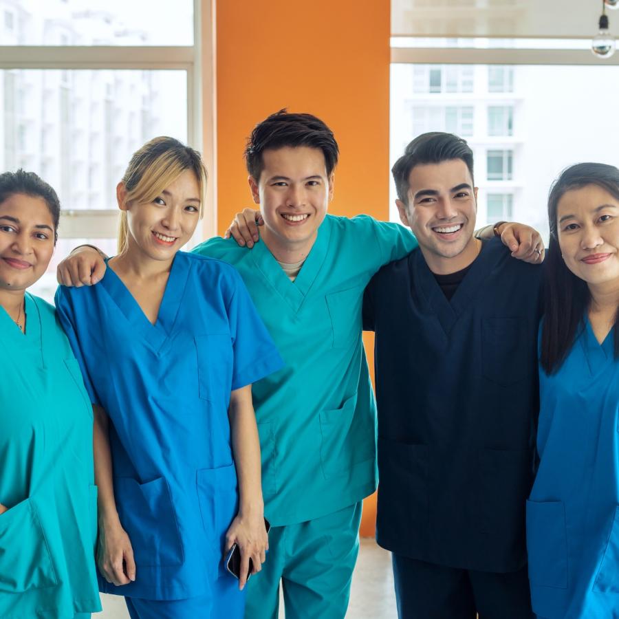 Five diverse nursing students in medical scrubs.