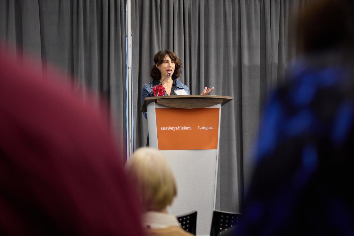 Instructor Jill Goldberg speaks to a crowd from a podium.