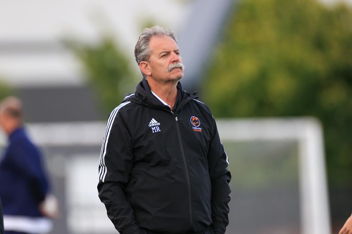 Coach Rizzardo in a Langara Falcon jacket on a soccer field.