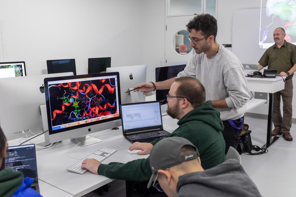 A male instructor shows students how to read DNA on a computer screen.