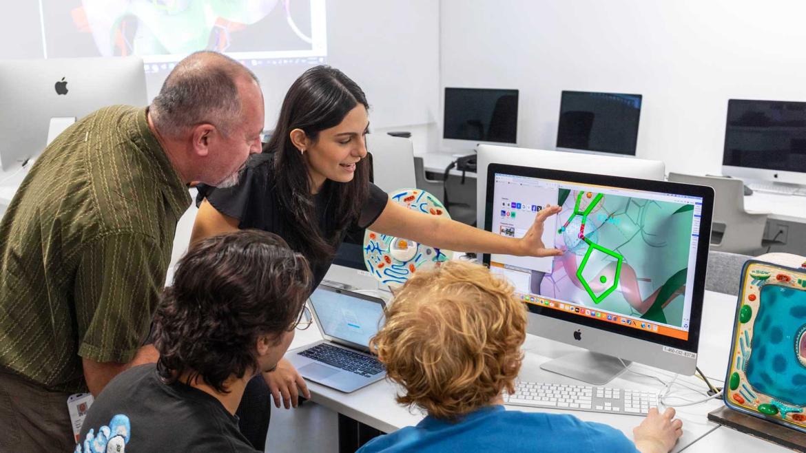 Instructor and a group of students analyzing Bioinformatics visuals on a computer screen.