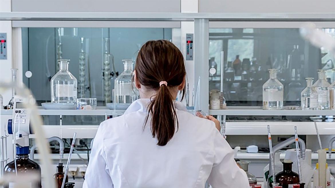A woman conducts research or technical support in a fully equipped laboratory.