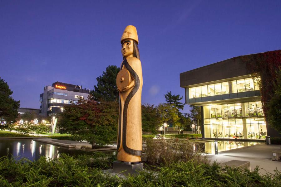 The Musqueam House Post near the Langara Pond at night.
